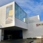 The outside of Lego House in Billund against a blue sky background.