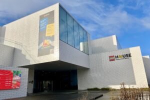 The outside of Lego House in Billund against a blue sky background.